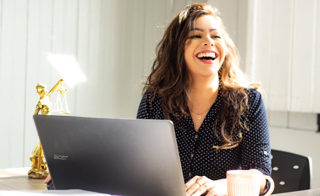パソコンを開き明るく笑う女性